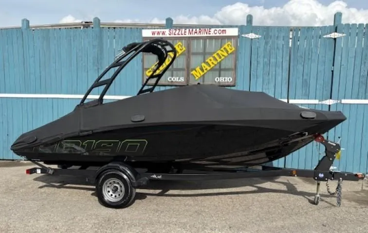 Slide: The Image of 2022 Yamaha AR190 boat with cover on trailer, parked by blue fence. - 32
