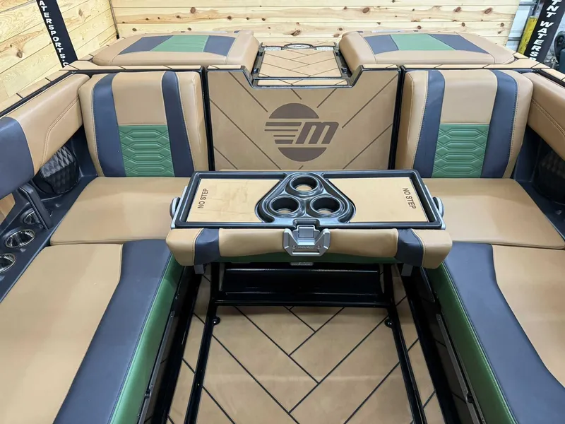 Slide: The Image of 2023 Malibu 25 LSV boat interior with tan and green seating, cup holders, and stylish design. - 9