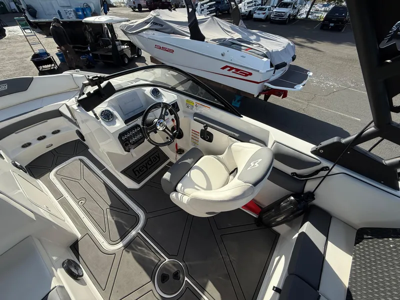 Slide: The Image of 2023 Heyday WT-2DC boat interior with steering wheel and seating, displayed outdoors. - 10