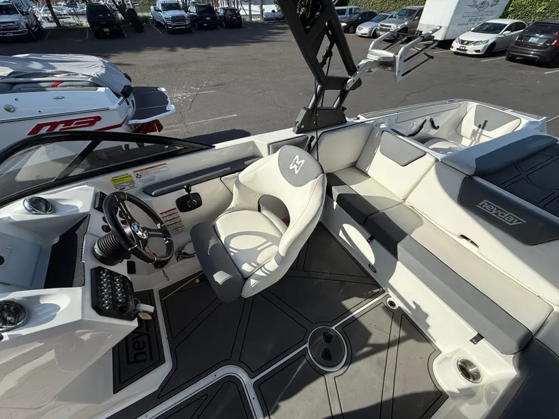 Slide: The Image of 2023 Heyday WT-2DC boat interior with steering wheel, seating, and dashboard in a parking lot. - 8