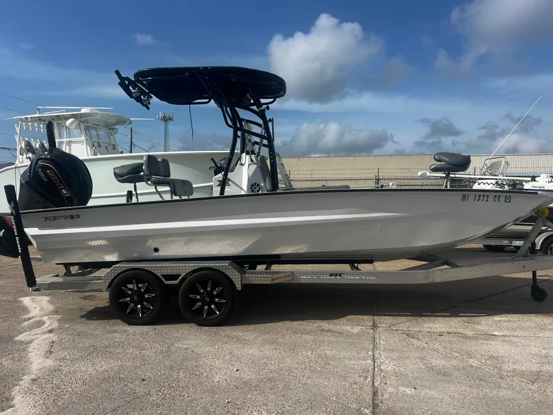 Slide: The Image of 2023 Xpress X23B Lounge boat on trailer, side view, under clear sky. - 0