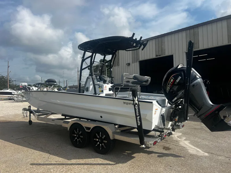 Slide: The Image of 2023 Xpress X23B Lounge boat on trailer, parked outdoors near a warehouse. - 1