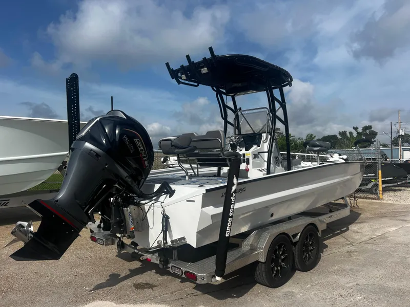 Slide: The Image of 2023 Xpress X23B Lounge boat with outboard motor on trailer, parked outdoors. - 2
