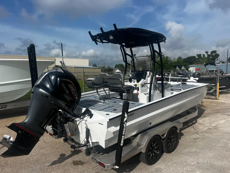 Slide: The Image of 2023 Xpress X23B Lounge boat with outboard motor on a trailer, parked outdoors. - 3