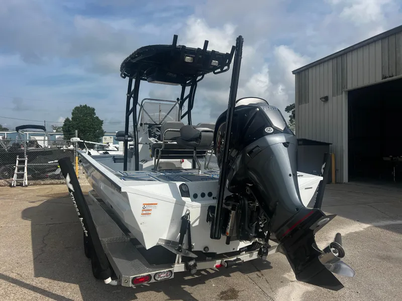Slide: The Image of 2023 Xpress X23B Lounge boat with outboard motor, parked near a warehouse. - 5
