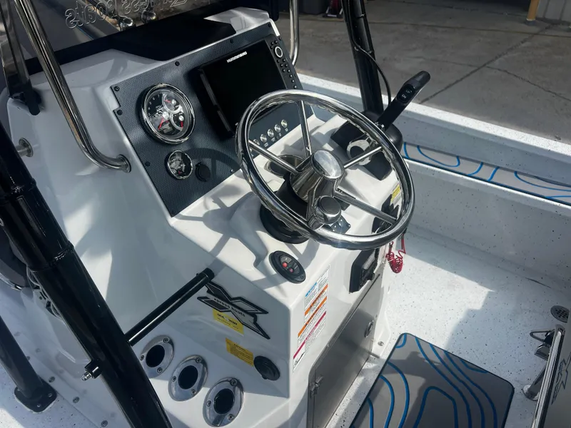 Slide: The Image of 2023 Xpress X23B Lounge boat dashboard with steering wheel and control panel. - 6