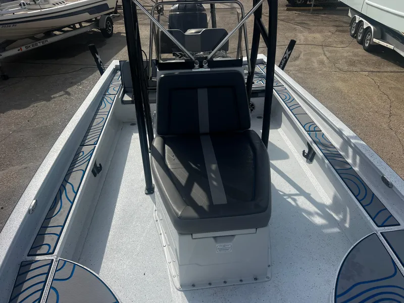 Slide: The Image of 2023 Xpress X23B Lounge boat interior with seating and console, parked outdoors. - 9