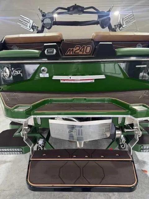 Slide: The Image of 2022 Malibu M240 boat, green and brown, rear view with wakeboard tower and swim platform. - 15