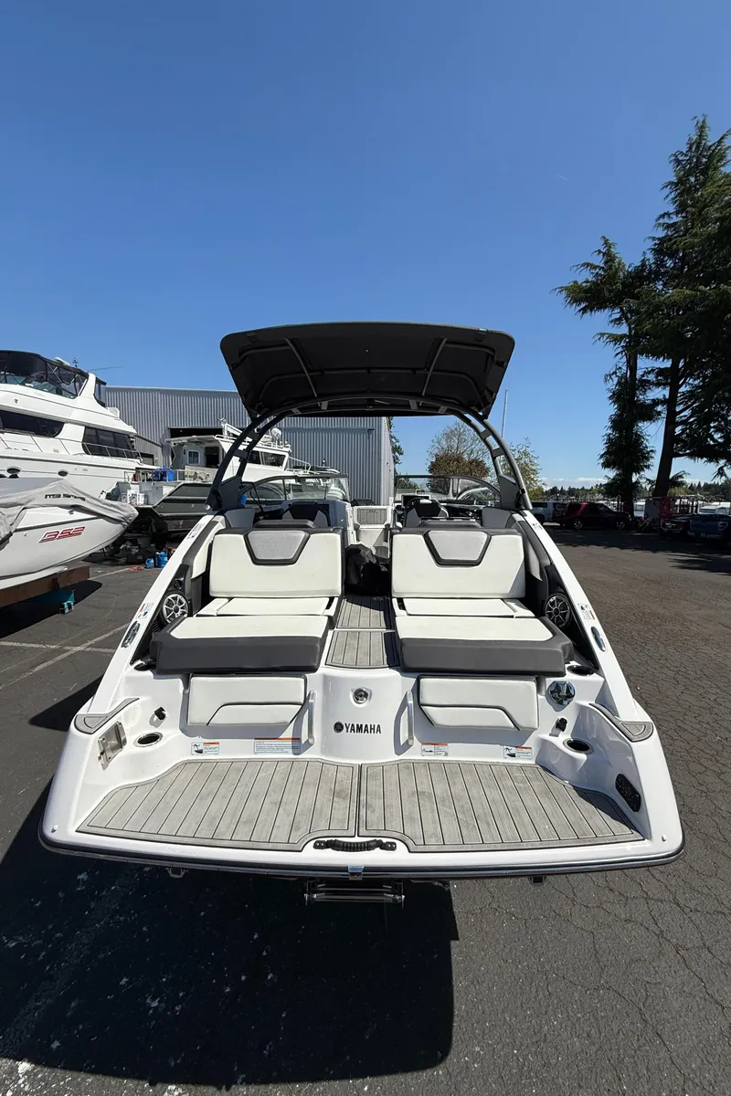 Slide: The Image of 2022 Yamaha Boats 252SD, rear view, showcasing seating and swim platform under clear blue sky. - 17