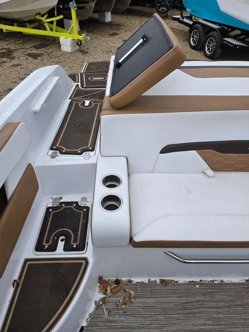 Slide: The Image of 2022 Four Winns HD2 I/O boat interior with white and brown seating, cup holders, and deck details. - 10