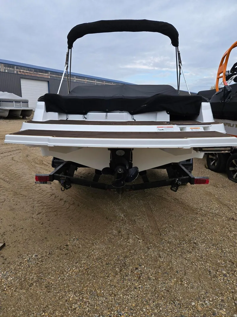 Slide: The Image of 2022 Four Winns HD2 I/O boat, rear view, parked on sandy ground. - 3