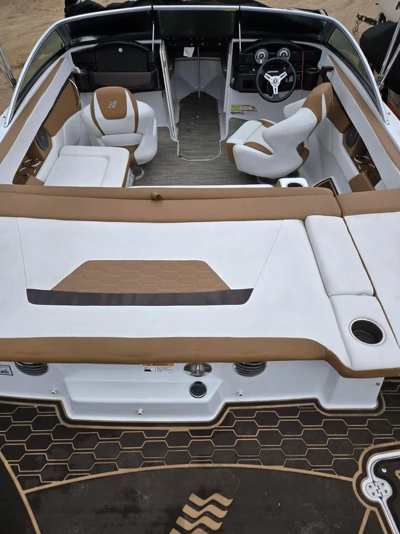 Slide: The Image of 2022 Four Winns HD2 I/O boat interior with tan and white seating, steering wheel, and dashboard. - 4