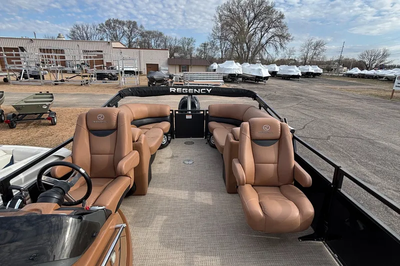 Slide: The Image of 2018 Regency R220LE3 pontoon boat with tan leather seats, parked outdoors. - 12
