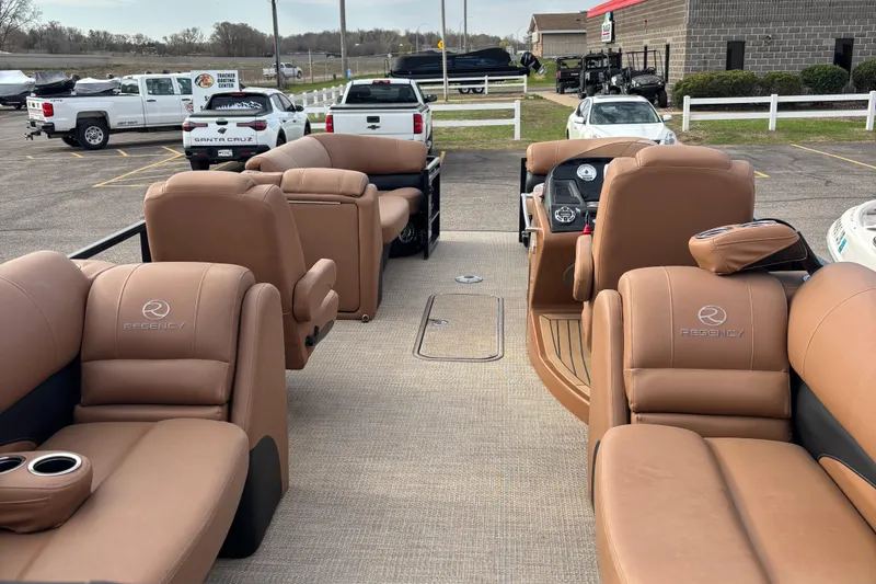 Slide: The Image of 2018 Regency R220LE3 pontoon boat with tan leather seating in a parking lot. - 7
