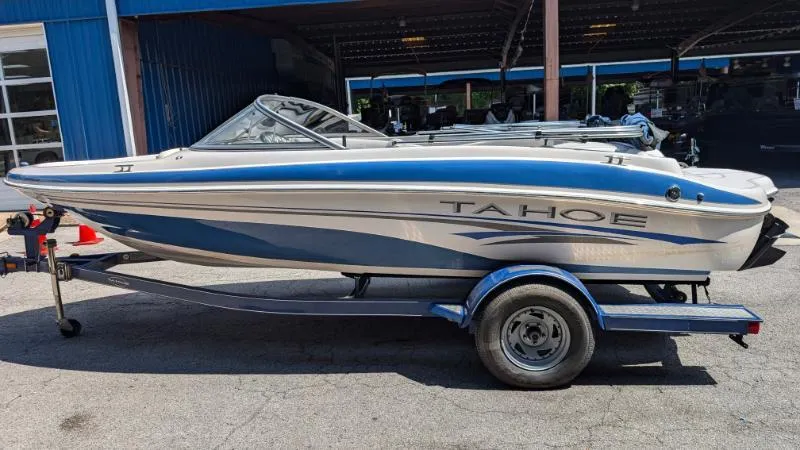Slide: The Image of 2006 Tahoe Q4 boat on trailer, parked outside a blue building. - 8