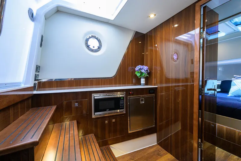 Slide: The Image of 2024 Cruisers Yachts GLS-OB interior with wood finish, microwave, and porthole window. - 22