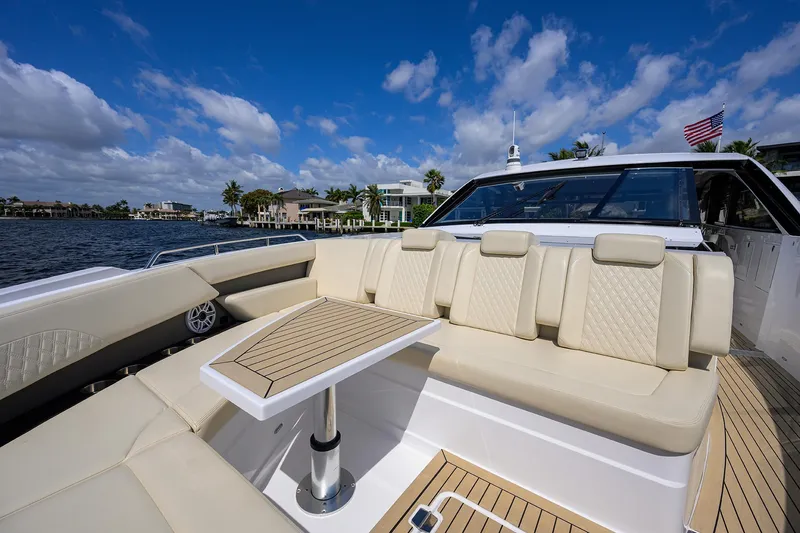 Slide: The Image of 2024 Cruisers Yachts GLS-OB luxury seating area with table, overlooking scenic waterfront. - 4