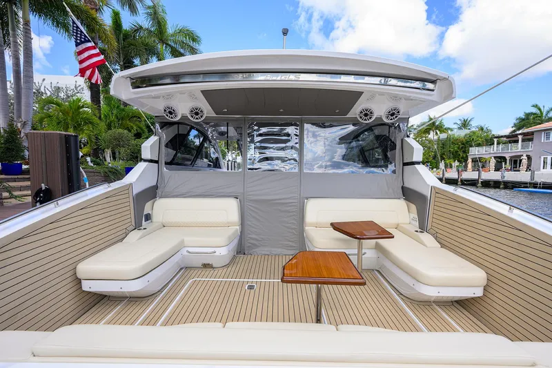 Slide: The Image of 2024 Cruisers Yachts GLS-OB luxury boat interior with seating and tables, docked near palm trees. - 42