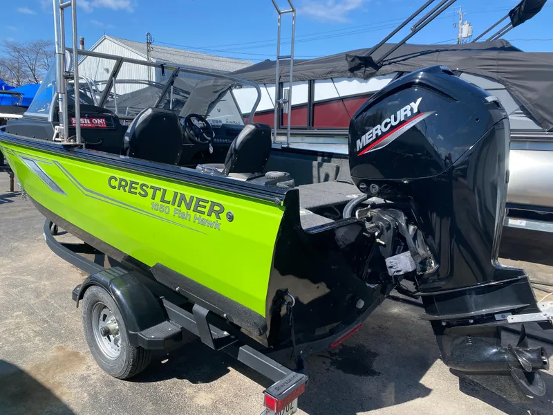 Slide: The Image of 2021 Crestliner FishHawk 1650 boat with Mercury engine, parked on a trailer. - 2