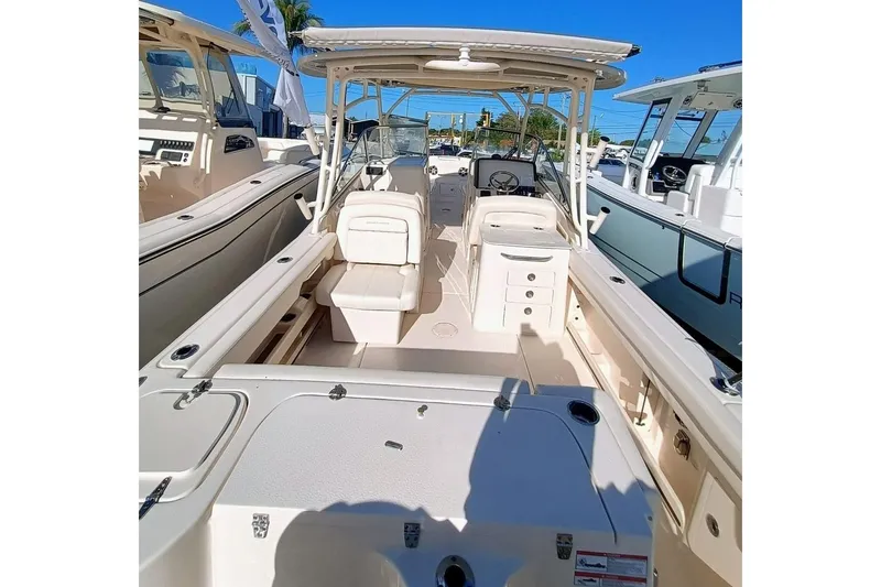 Slide: The Image of 2025 Grady-White Freedom 275 boat interior, showcasing seating and helm, docked under clear skies. - 4