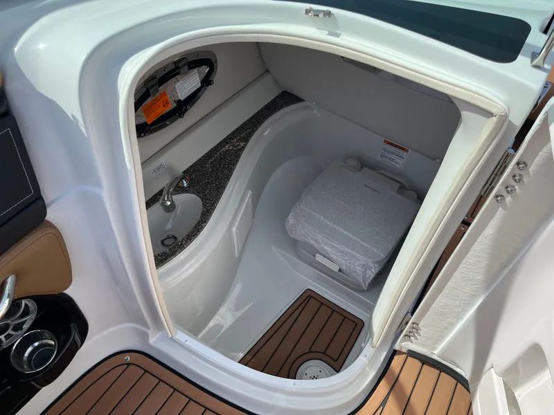 Slide: The Image of 2025 Crownline Eclipse E235 boat interior with compact bathroom and wooden flooring. - 14