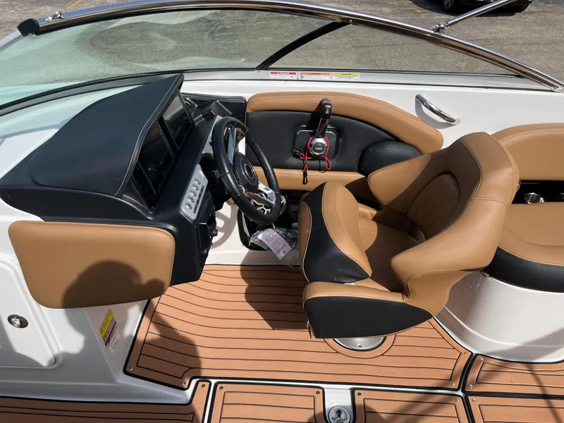 Slide: The Image of 2025 Crownline Eclipse E235 boat interior with tan and black seating, modern dashboard, and wood-style flooring. - 15