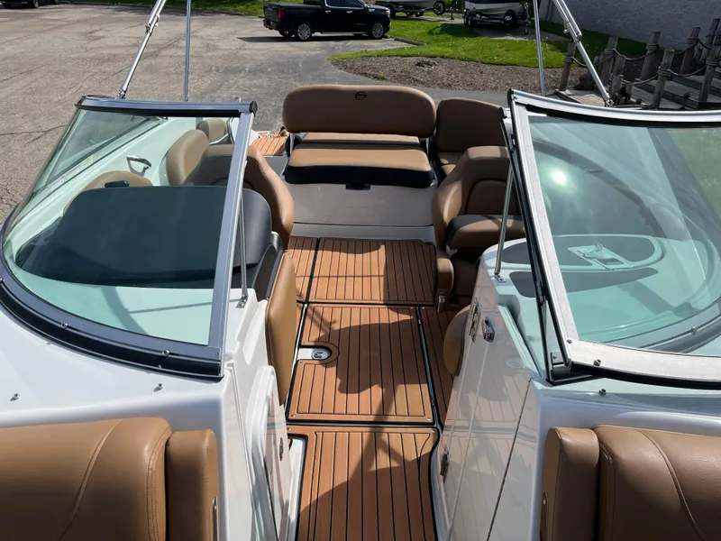 Slide: The Image of 2025 Crownline Eclipse E235 boat interior with tan seating and wood-style flooring. - 5