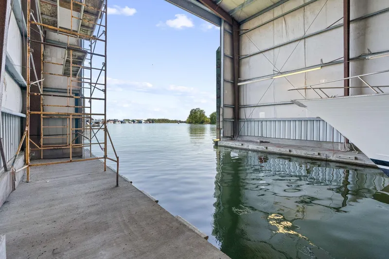 Slide: The Image of Boathouse interior with water view, scaffolding, and partial boat, Custom Larson Boathouse, 1985. - 14