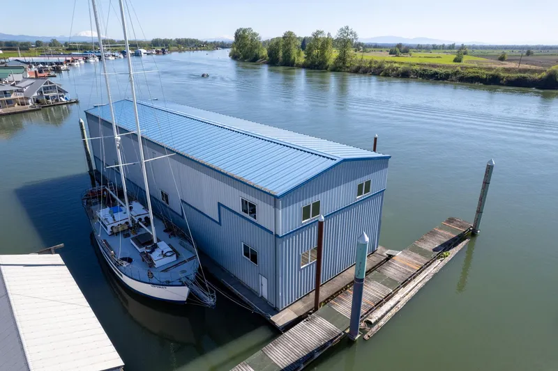 Slide: The Image of Aerial view of 1985 Custom Larson Boathouse with sailboat on a serene river. - 19