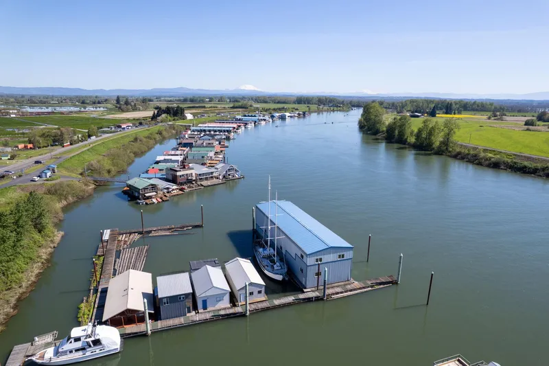 Slide: The Image of Aerial view of 1985 Custom Larson Boathouse on a serene river with surrounding greenery. - 25