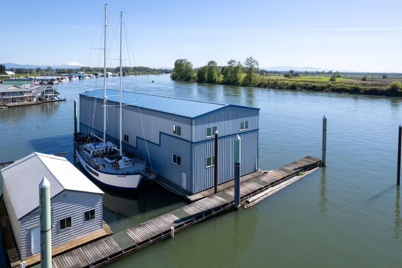 Slide: The Image of A 1985 Custom Larson Boathouse with sailboat on a serene river. - 29