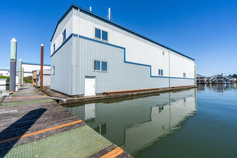 Slide: The Image of Large 1985 Custom Larson Boathouse on calm water, clear blue sky background. - 3