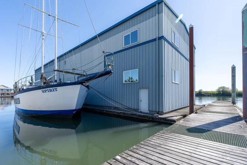 Slide: The Image of Sailboat docked beside 1985 Custom Larson Boathouse on calm water. - 30