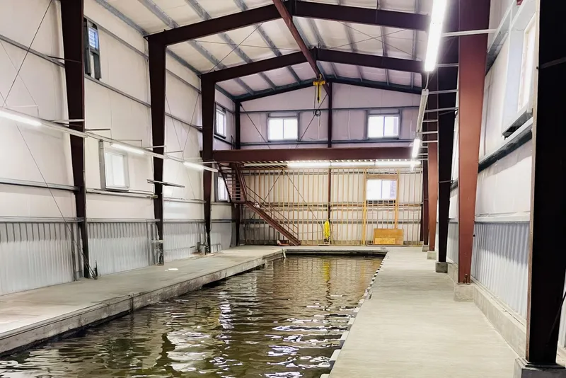 Slide: The Image of Spacious 1985 Custom Larson Boathouse interior with water channel and metal structure. - 5