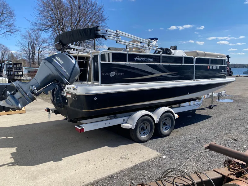 Slide: The Image of 2014 Hurricane Fundeck 216 boat on trailer, parked near waterfront under clear blue sky. - 4