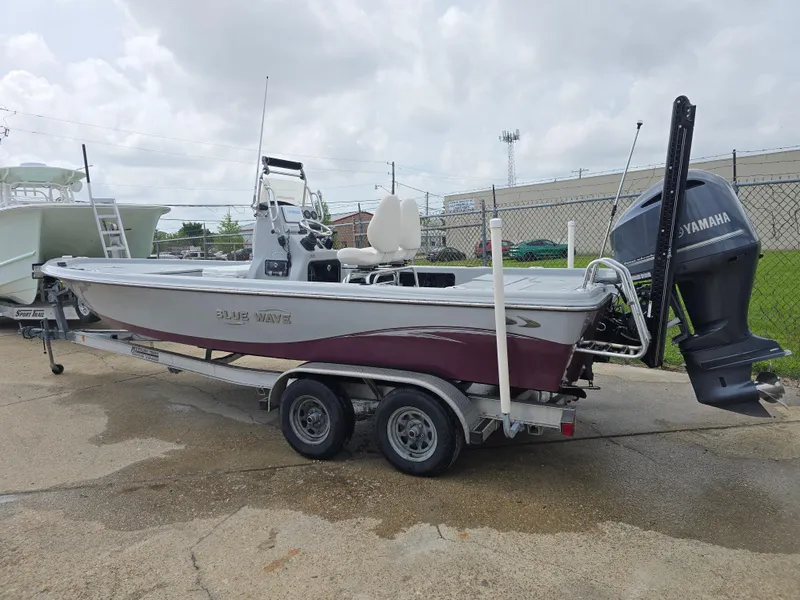 Slide: The Image of 2016 Blue Wave 2400 PureBay boat on trailer with Yamaha outboard motor, parked outdoors. - 5