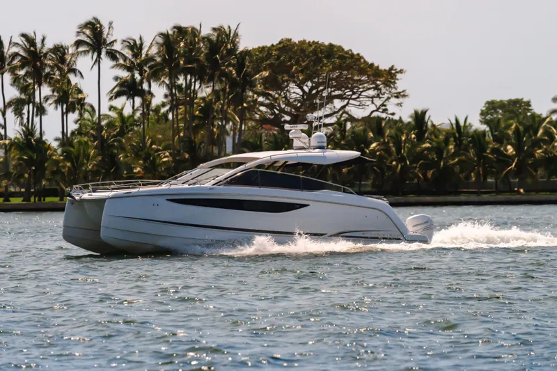Slide: The Image of 2023 Four Winns TH36 OB cruising on a tropical waterway with palm trees in the background. - 4