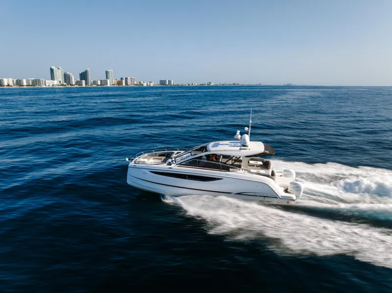 Slide: The Image of 2023 Four Winns TH36 OB yacht cruising on open water near a city skyline. - 5