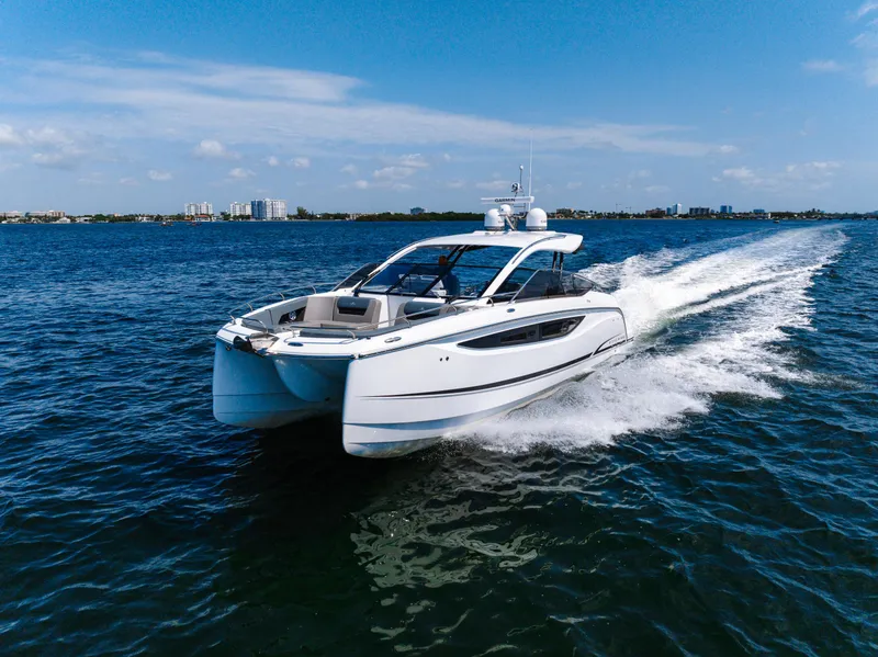 Slide: The Image of 2023 Four Winns TH36 OB cruising on open water under a clear blue sky. - 6