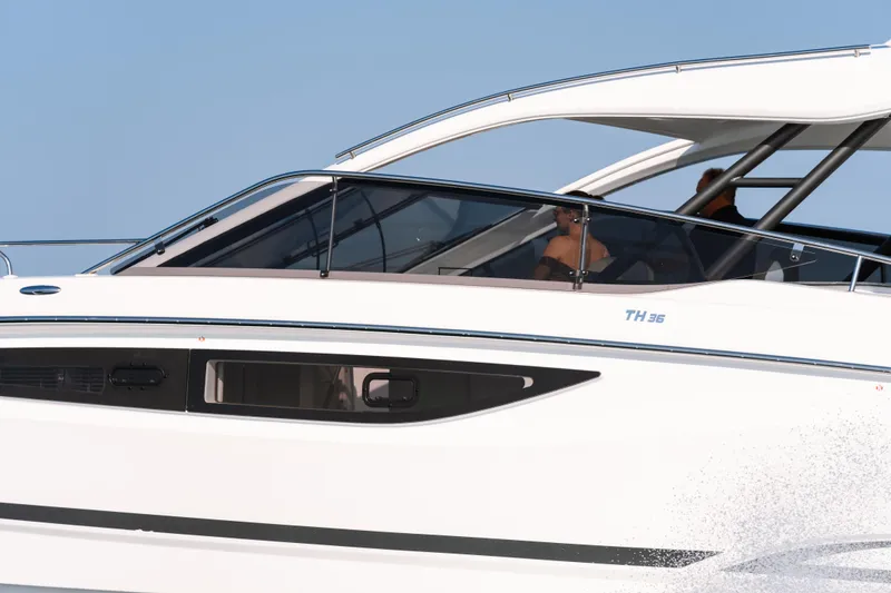 Slide: The Image of 2023 Four Winns TH36 OB boat cruising on water, sleek design, side view. - 9