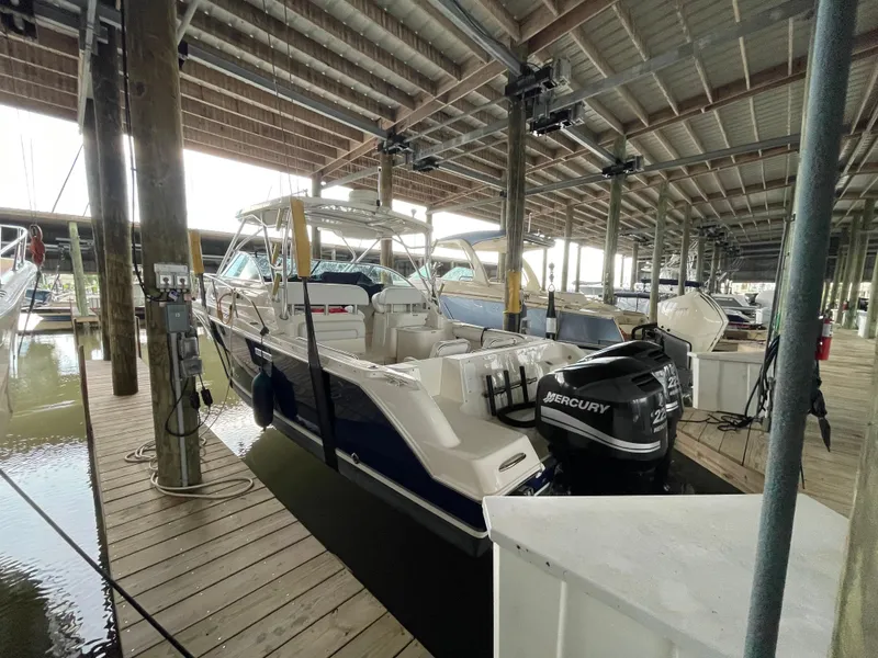 Slide: The Image of 2004 Wellcraft 290 Coastal boat docked under a covered marina with Mercury outboard engines. - 11