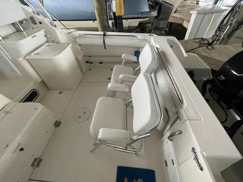 Slide: The Image of 2004 Wellcraft 290 Coastal boat interior with white seating and storage compartments. - 23