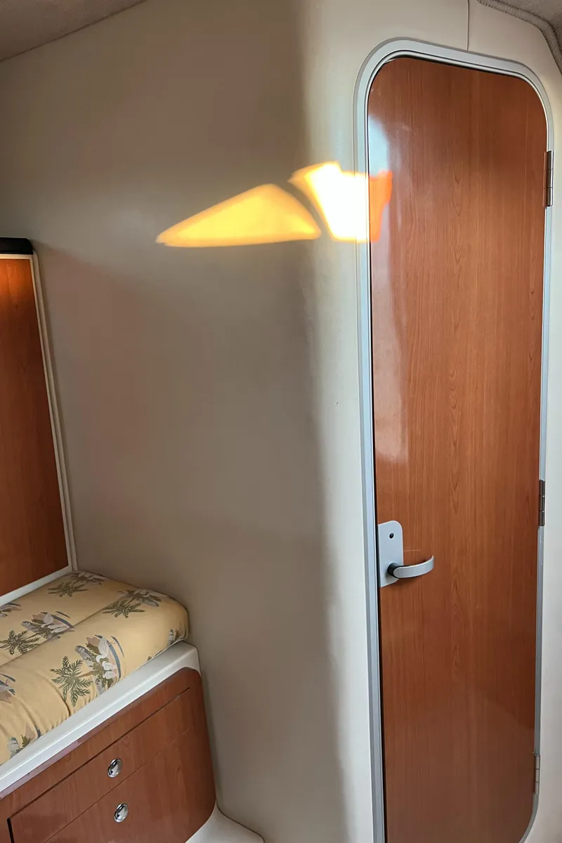 Slide: The Image of 2004 Wellcraft 290 Coastal cabin interior with wooden door and patterned bedding. - 26