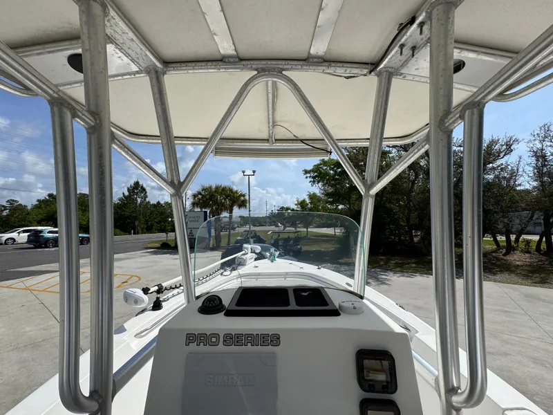Slide: The Image of 2011 Sea Fox 236 Center Console boat, view from helm, featuring T-top and console controls. - 34
