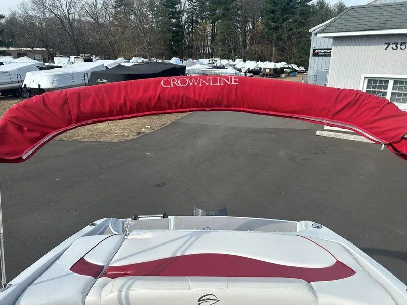 Slide: The Image of 2013 Crownline 21 SS boat with red canopy in a storage area. - 21