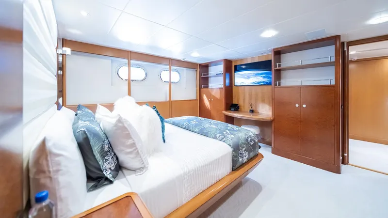 Slide: The Image of Luxurious bedroom interior on 1997 Feadship TASIA yacht, featuring elegant wood finishes and plush bedding. - 19