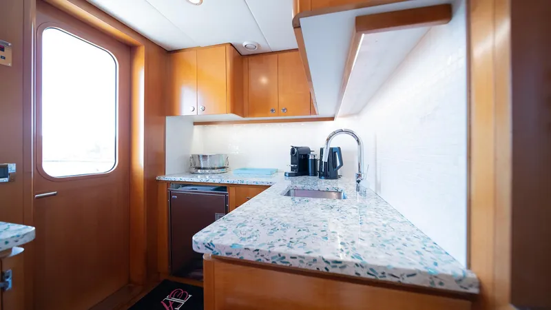 Slide: The Image of Compact yacht kitchen with modern appliances, wooden cabinetry, and speckled countertop on Feadship TASIA, 1997. - 43