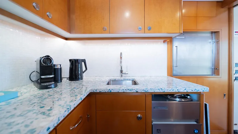 Slide: The Image of Luxurious yacht kitchen with modern appliances, marble countertop, and wooden cabinetry on Feadship TASIA, 1997. - 44