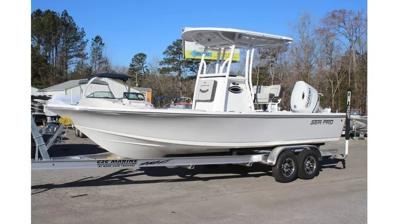 Slide: The Image of 2025 Sea Pro 230 Bay boat on trailer, parked outdoors, side view. - 1