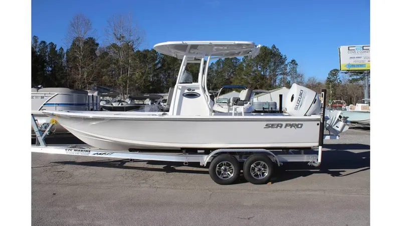 Slide: The Image of 2025 Sea Pro 230 Bay boat on trailer, parked outdoors, clear sky background. - 2